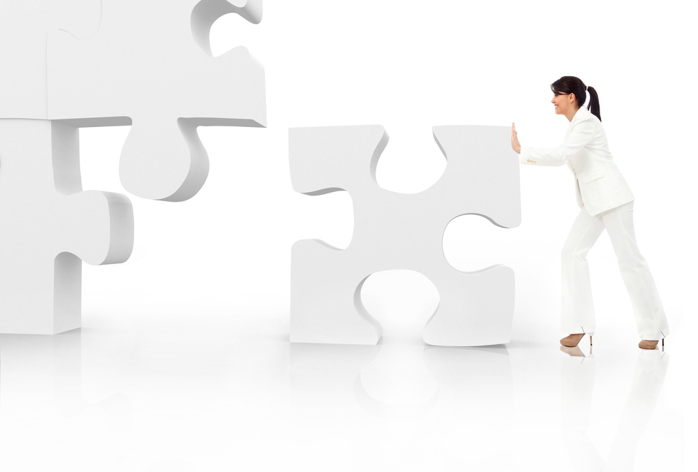 Asian business woman building a puzzle - isolated over a white background